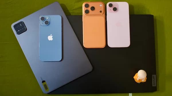 Three iphones and a tablet on a green surface.