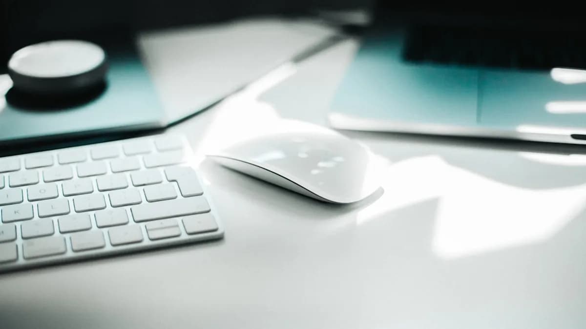 Apple Magic mouse beside keyboard on white surface