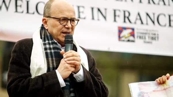 a man speaking into a microphone in front of a sign