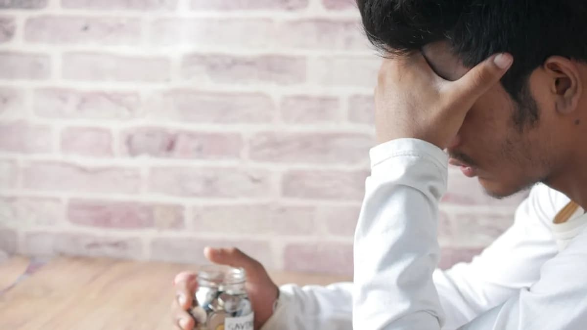 a man sitting at a table with a jar of coins