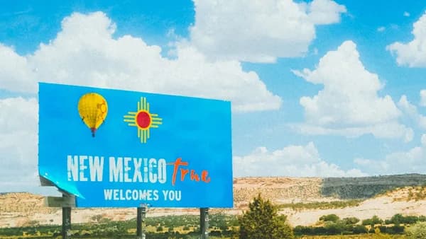 a blue sign that says new mexico plaza welcomes you