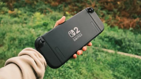 Hand holding a black nintendo switch lite outdoors