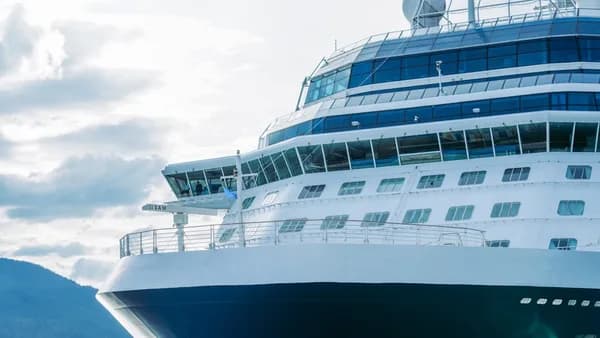 A large cruise ship in the water with mountains in the background