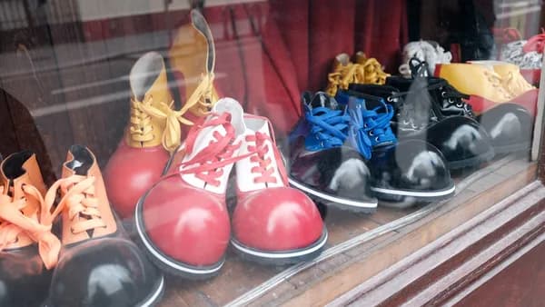 Assortment of colorful clown shoes displayed in a window.