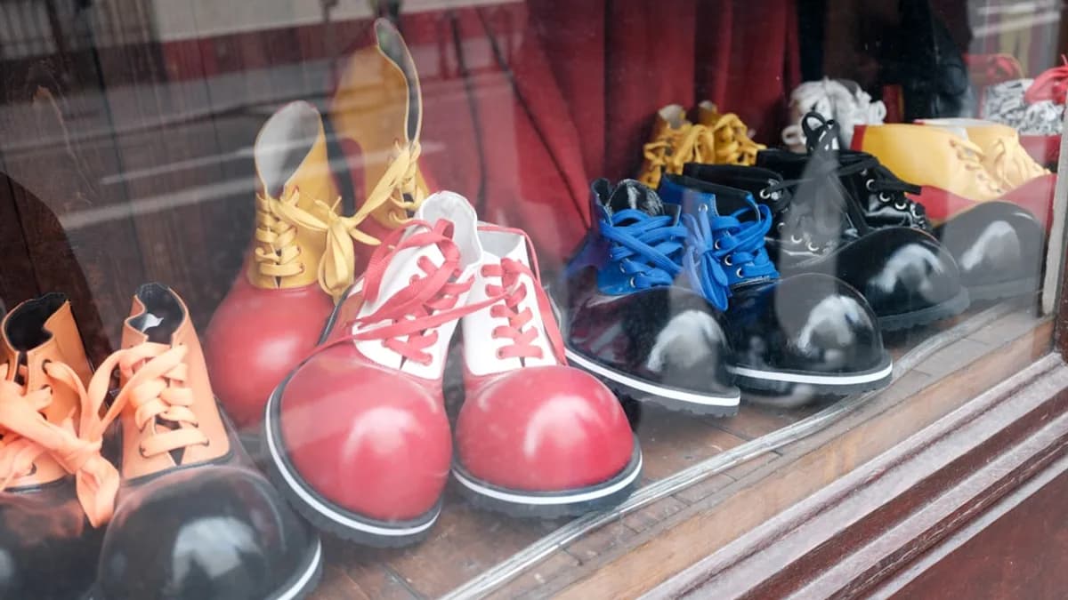 Assortment of colorful clown shoes displayed in a window.