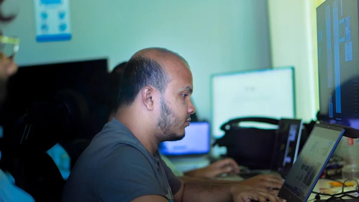 Man working on a laptop in an office setting.