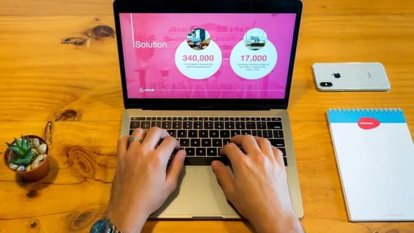 person using macbook pro on brown wooden table