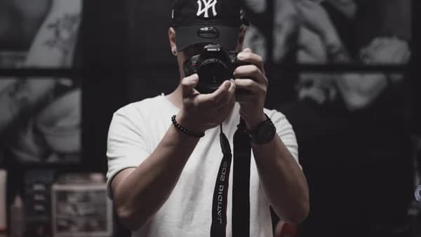 man in white crew neck t-shirt holding black dslr camera