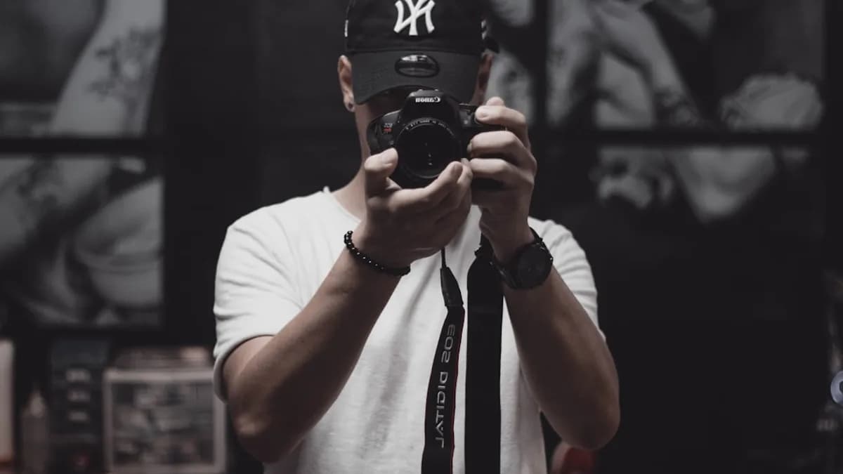 man in white crew neck t-shirt holding black dslr camera