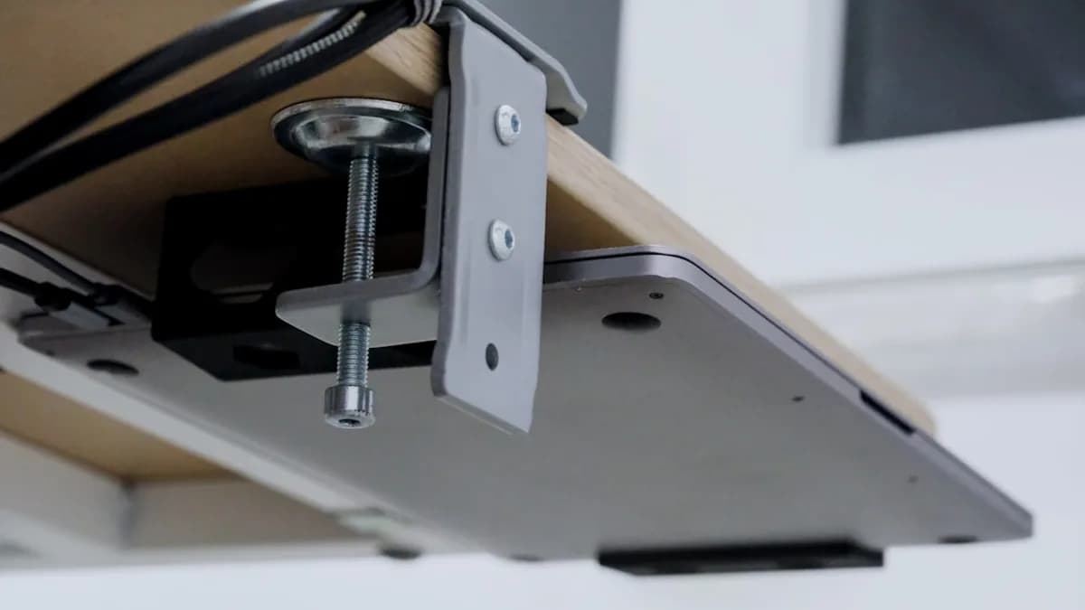 Laptop clamped under a wooden desk with cables.