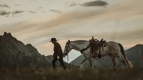 man in red jacket standing beside white horse during daytime