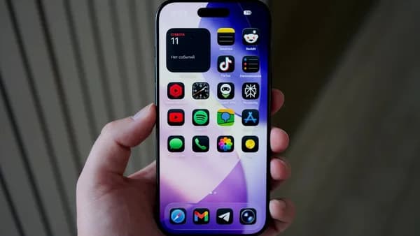 Hand holding a smartphone with colorful apps displayed.