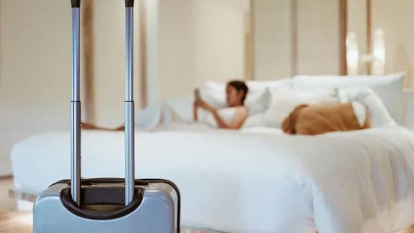 a woman laying on a bed with a suitcase in front of her