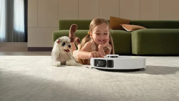 Girl and dog watch robot vacuum cleaner