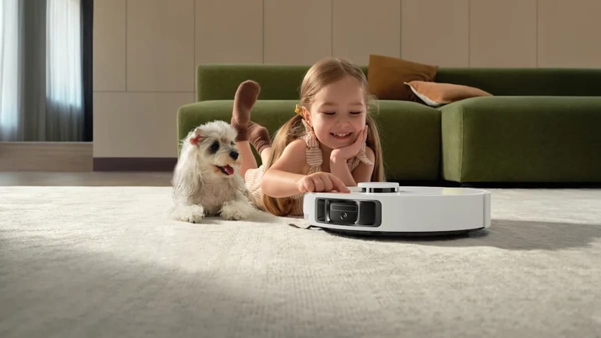 Girl and dog watch robot vacuum cleaner