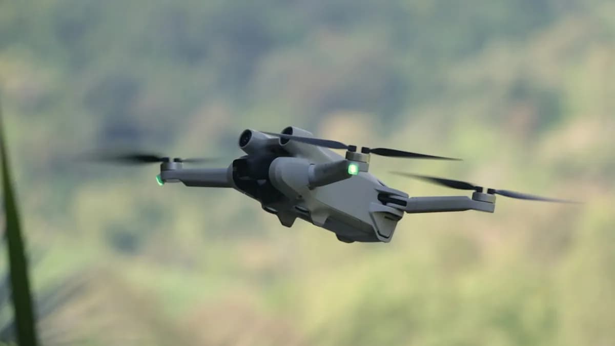a small gray helicopter flying over a lush green hillside