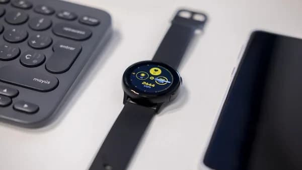 round black watch beside gray keyboard