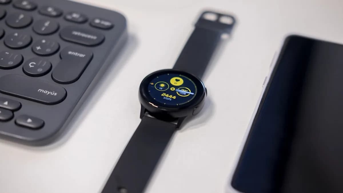 round black watch beside gray keyboard
