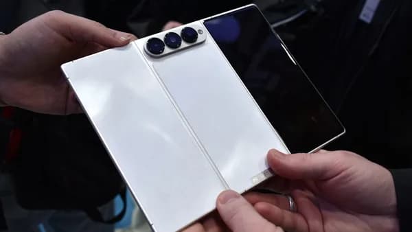 Hands hold a white foldable smartphone with three cameras.