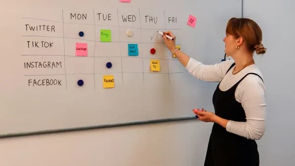 a woman writing on a white board with sticky notes