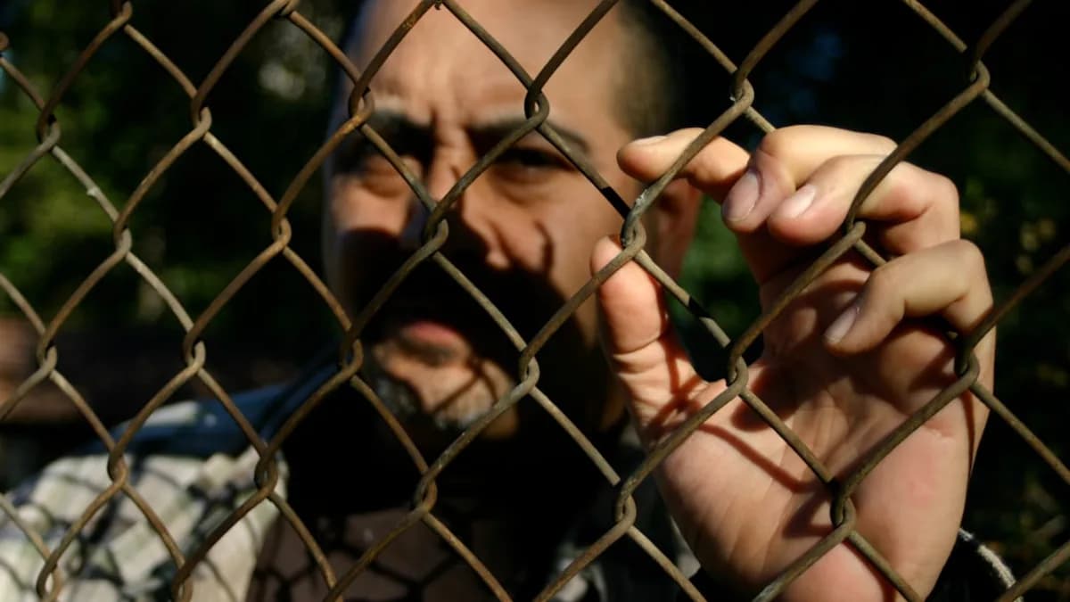 a man behind a chain link fence making a face