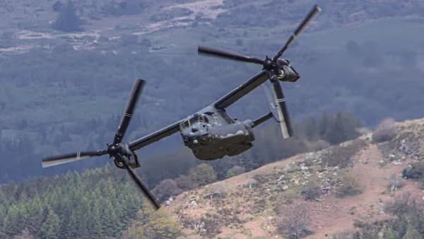 a helicopter flying over a lush green hillside