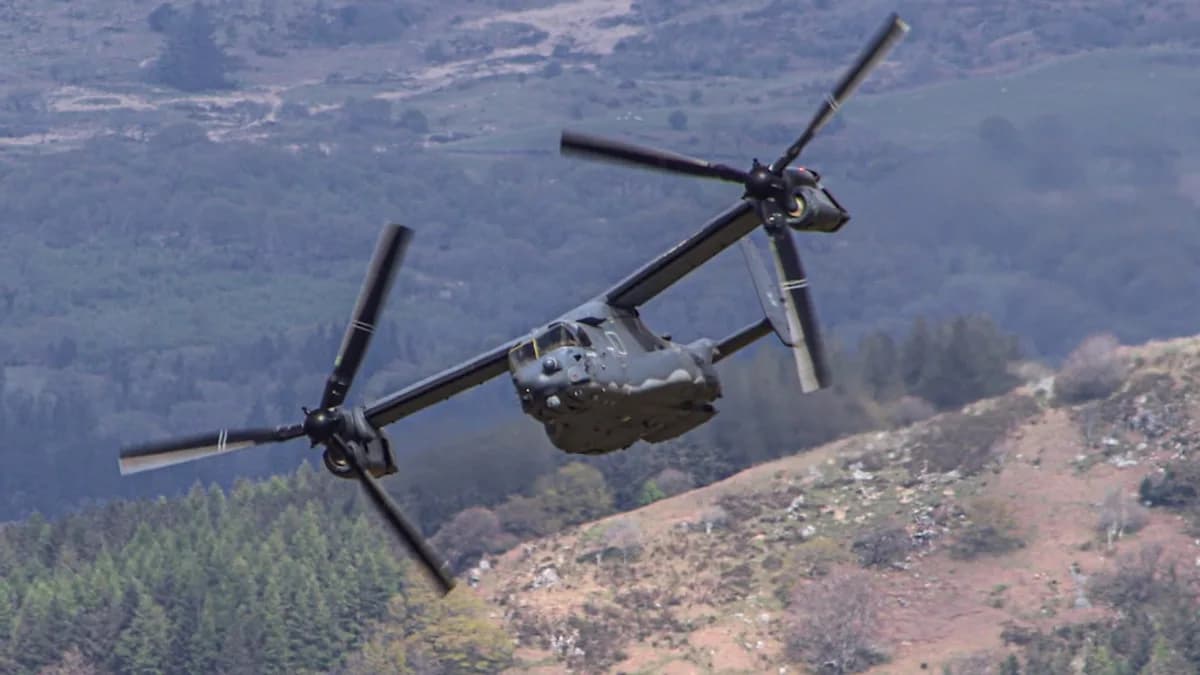 a helicopter flying over a lush green hillside