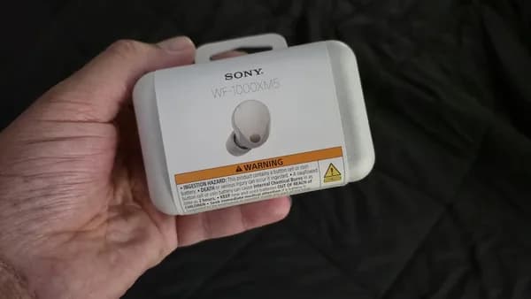 Sony earbuds in original packaging held by hand