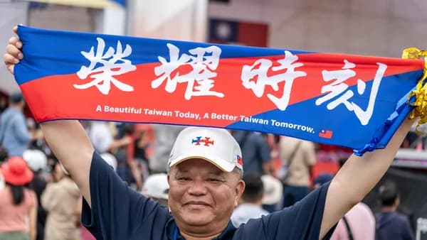A man holding up a blue and red scarf