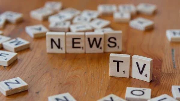 A wooden table topped with scrabble tiles spelling news
