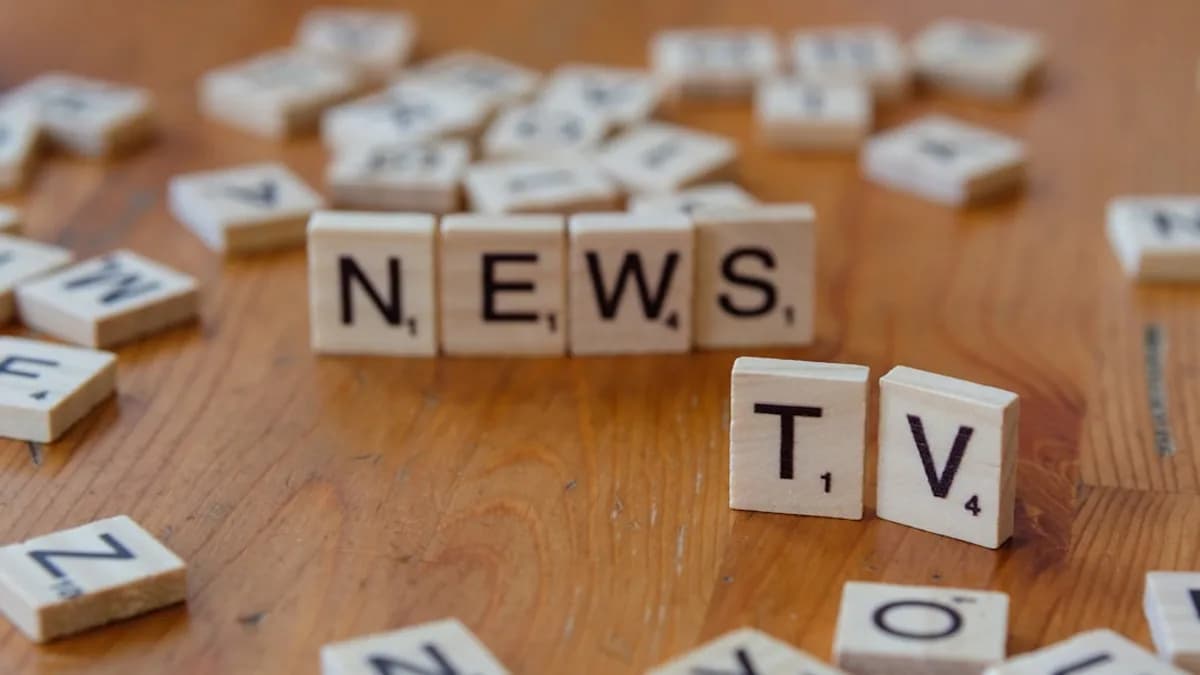 A wooden table topped with scrabble tiles spelling news