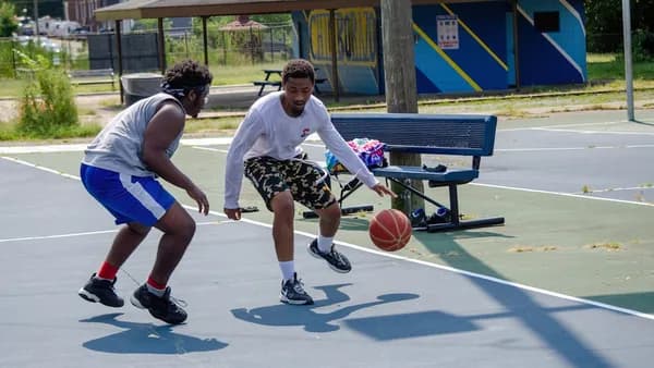two young men playing a game of basketball on a court
