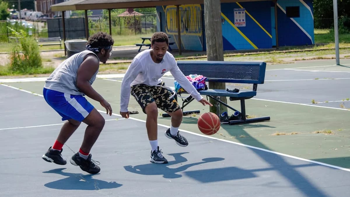two young men playing a game of basketball on a court