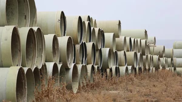 a large stack of pipes sitting in the middle of a field