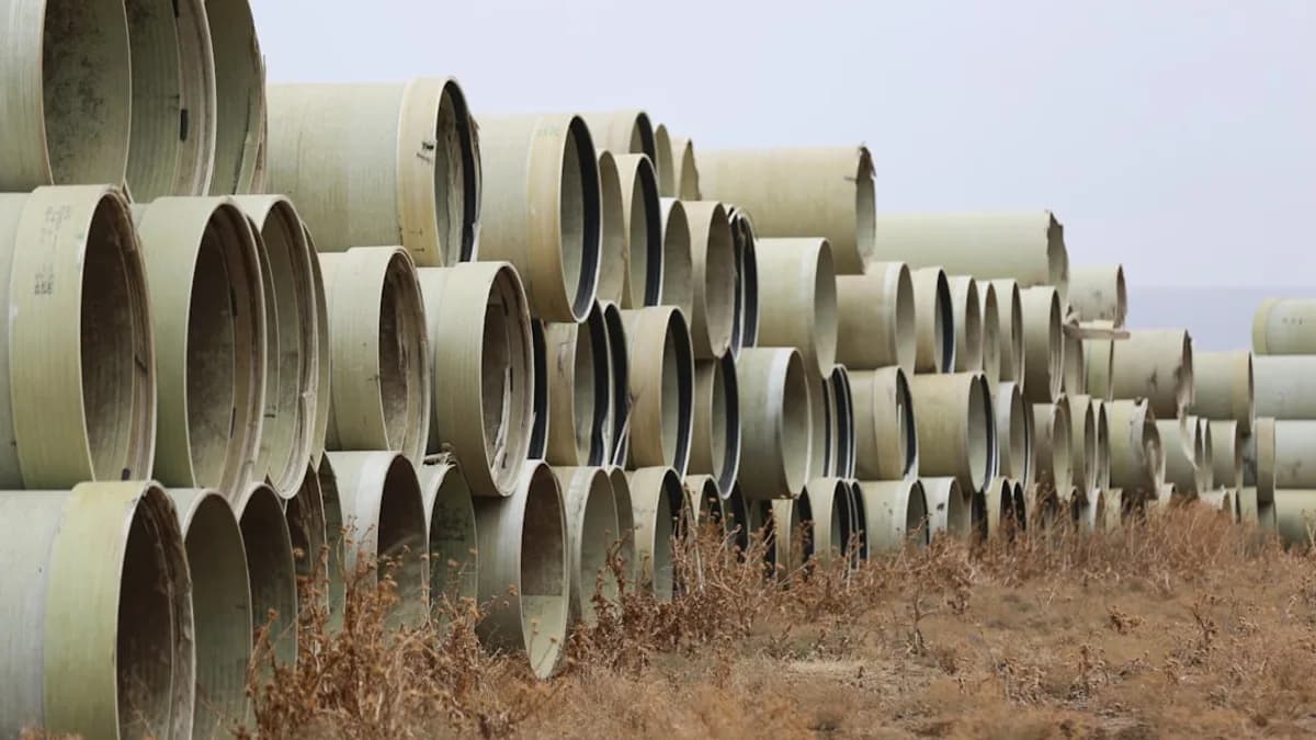 a large stack of pipes sitting in the middle of a field