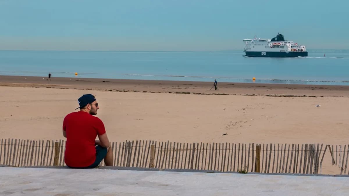 man wearing red shirt sitting on seashore