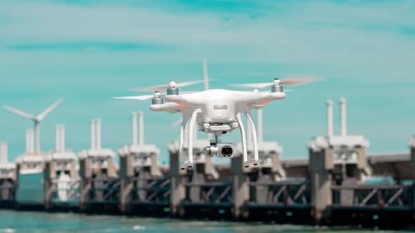 selective focus photography of white drone hovering above body of water
