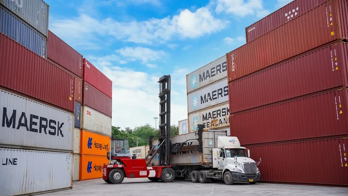 Forklift moving shipping containers at a port.