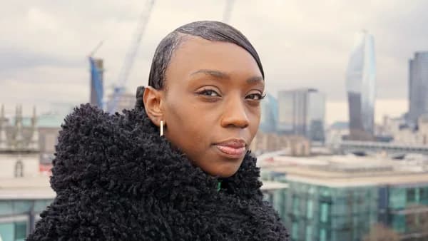 a woman in a black coat looking at the camera