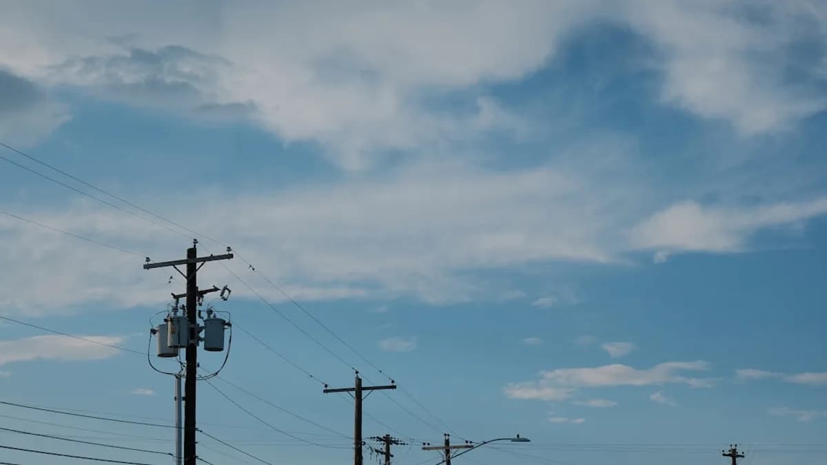 Utility poles and wires against a cloudy blue sky