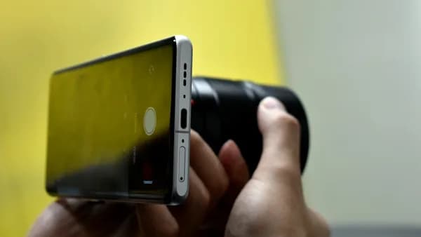 Hands holding a smartphone and camera lens