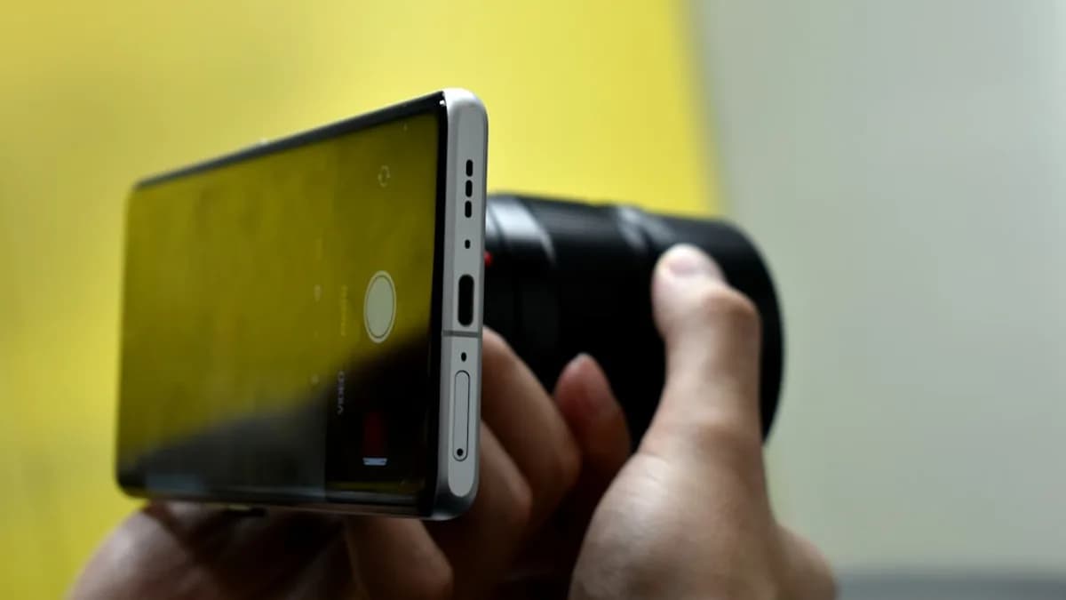 Hands holding a smartphone and camera lens