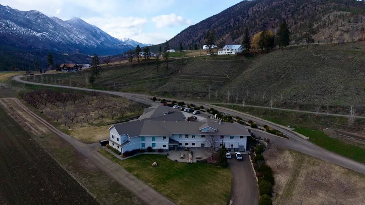 Building nestled in a valley with mountains behind