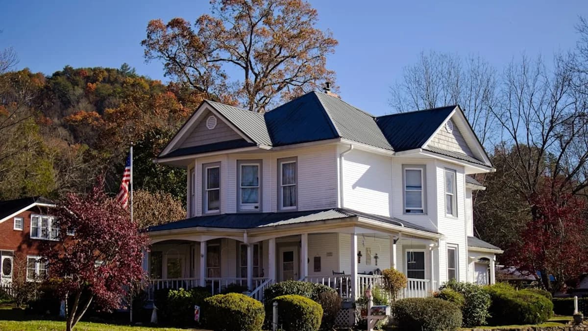 A white two-story house with a wraparound porch.