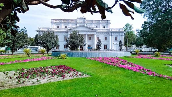 a large white building sitting on top of a lush green field