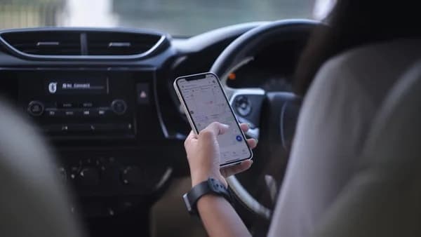 A woman holding a cell phone while driving a car