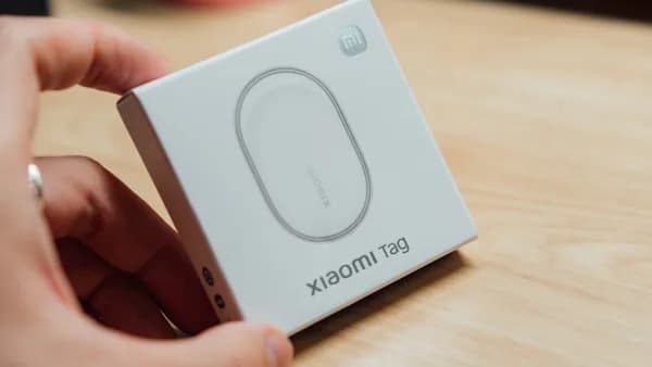 Hand holding a white box with "xiaomi tag" printed