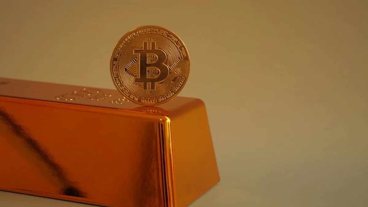 Bitcoin coin resting on a gold bar.