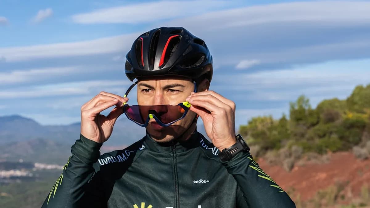 a man wearing a helmet and holding a pair of sunglasses