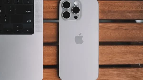 An iPhone and a laptop on a wooden table